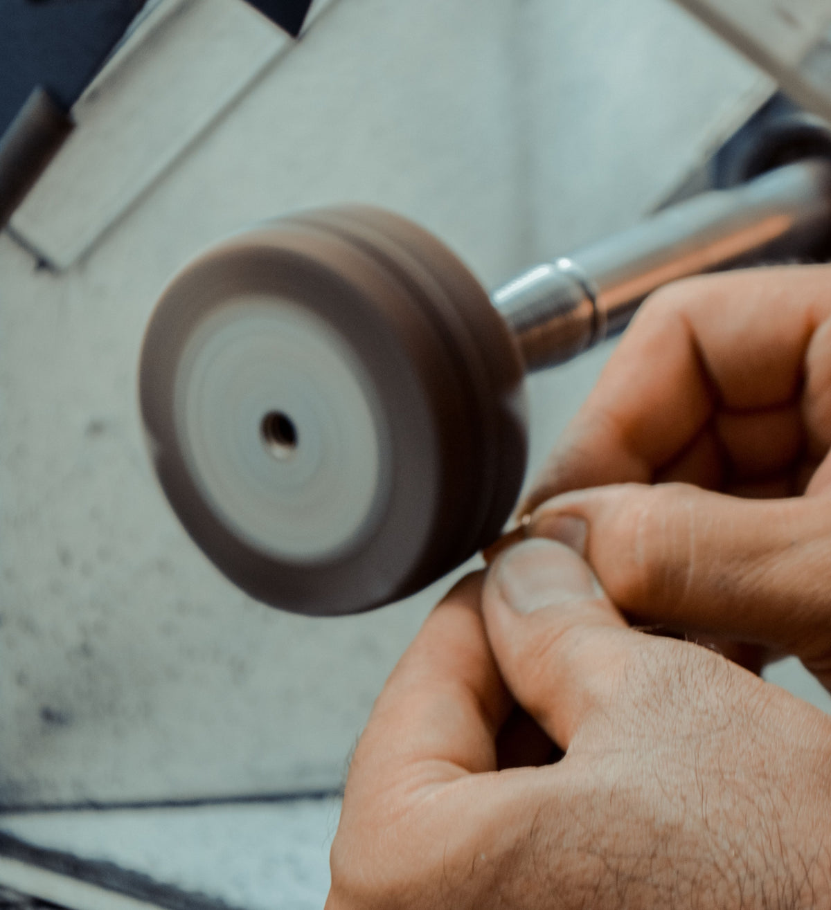 A goldsmith at the bench, hands close on a piece of gold.